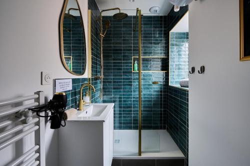 une salle de bain avec un lavabo et une douche avec du carrelage bleu dans l'établissement Le Jungle, à Dijon