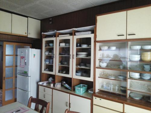 富士宮市にあるゲストハウスFace to Faceのキッチン(白いキャビネット、白い冷蔵庫付)