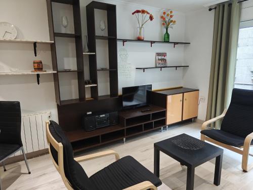ein Wohnzimmer mit einem Fernseher und zwei Stühlen und einem Tisch in der Unterkunft Apartamento en Ribeira in Ribeira