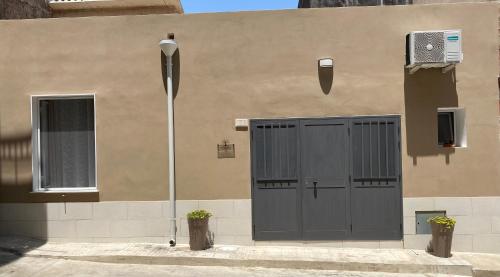 ein Gebäude mit zwei grauen Türen und einem Fenster in der Unterkunft Il Cortiletto Casa Vacanze in Pachino