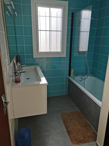 La salle de bains est pourvue d'un lavabo, d'une baignoire et d'une fenêtre. dans l'établissement La Villa, à La Tranche-sur-Mer