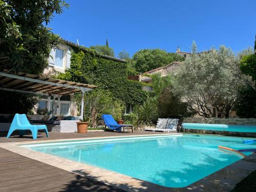 une piscine avec des chaises bleues et une maison dans l'établissement Maison de caractère pour vacances ou travail, à Teyran