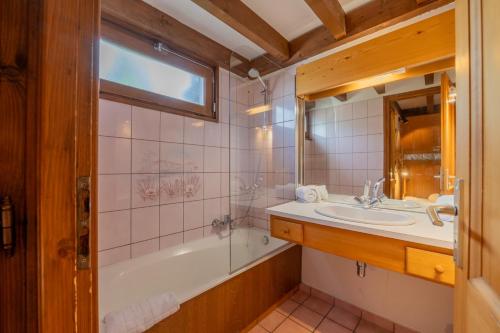 une salle de bain avec une baignoire et un lavabo et une baignoire tubermottermott dans l'établissement La Corniche A18 - Snow and Trek, à Morzine