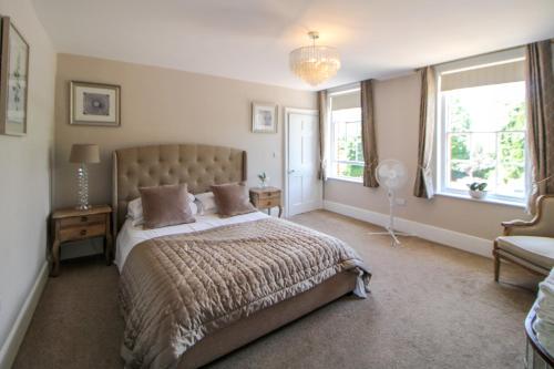 a bedroom with a bed and a chair and windows at The Fraya Suite at Sterling house Short Stays in Basingstoke