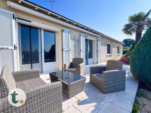 a group of wicker chairs and a table on a patio at Tranquiloue - Maison de Campagne - PuyduFou in Treize-Vents