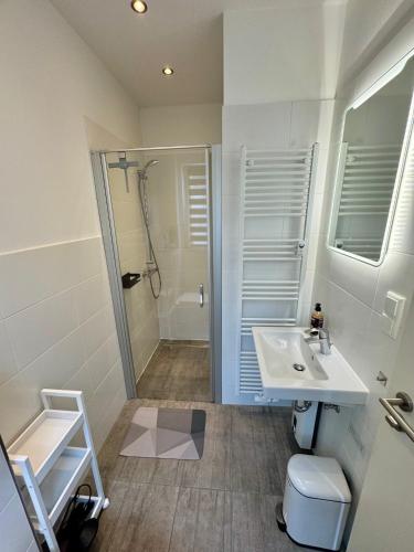 a white bathroom with a sink and a shower at Bungalow Benther Berg, Contactless Check-in, Vollsaniert und Renoviert 2025 in Ronnenberg