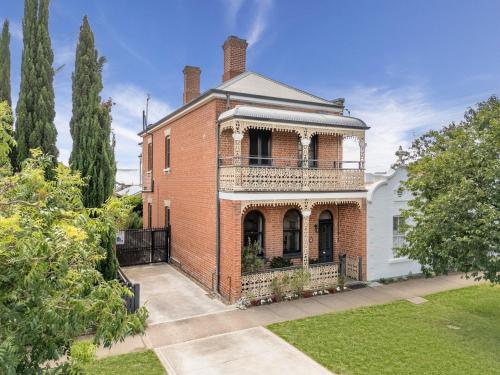 an old brick house with a balcony on a yard at Historical home is a cosy stay located in central Bathurst in Bathurst