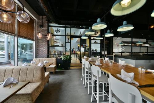 Un restaurante con mesas de madera y sillas blancas. en Park Inn By Radisson Istanbul Ataturk Airport, en Estambul