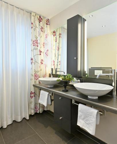 a bathroom with two sinks and a large mirror at Landhaushotel Hof Wasserkuppe in Poppenhausen