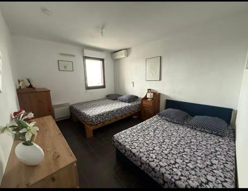 une chambre avec deux lits et une table dans une pièce dans l'établissement Le Refuge Du Sud, à Montpellier