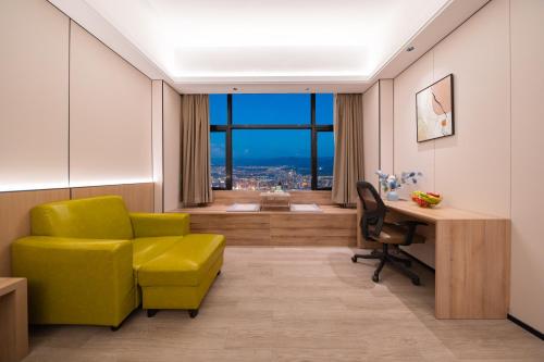 Una habitación con una silla amarilla y un escritorio y una ventana. en Yunduo Hotel Puning International Commodity City Branch, en Puning