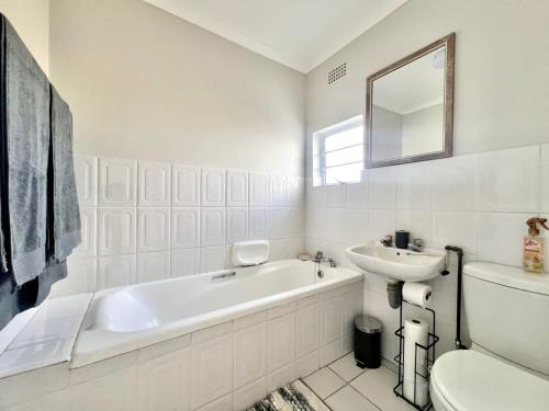 a white bathroom with a tub and a sink at Fijnbosch Villa at Claptons in Jeffreys Bay