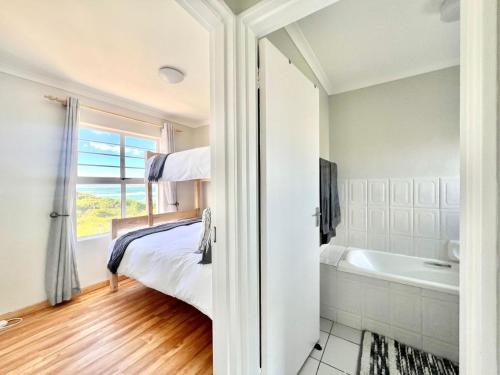 a bedroom with a bed and a bath tub at Fijnbosch Villa at Claptons in Jeffreys Bay
