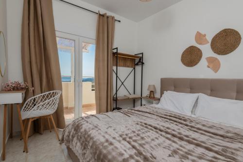 a bedroom with a bed and a desk and a window at Askos Suites in Agios Nikolaos
