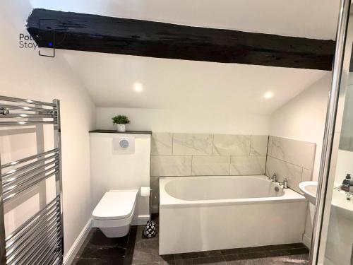 a bathroom with a tub and a toilet and a sink at No 2 PolkaStays Ivy Farm Rosewood Cottage in Plumpton