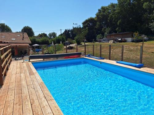 une grande piscine bleue avec une terrasse en bois dans l'établissement The Lodge Gite, à Saint-Privat-des-Prés