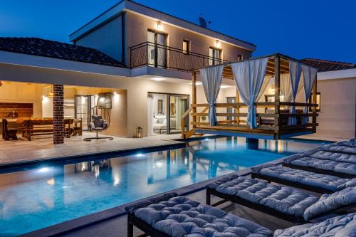 a swimming pool with two loungers in front of a house at Villa Alba ZadarVillas in Vrana