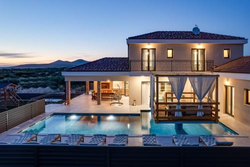 a villa with a swimming pool in front of a house at Villa Alba ZadarVillas in Vrana