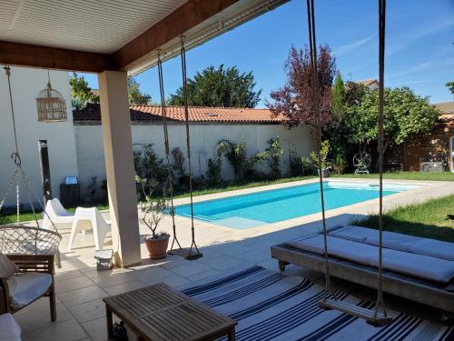 une terrasse couverte avec une balançoire et une piscine dans l'établissement Villa Azur Piscine et parking, à Castelginest
