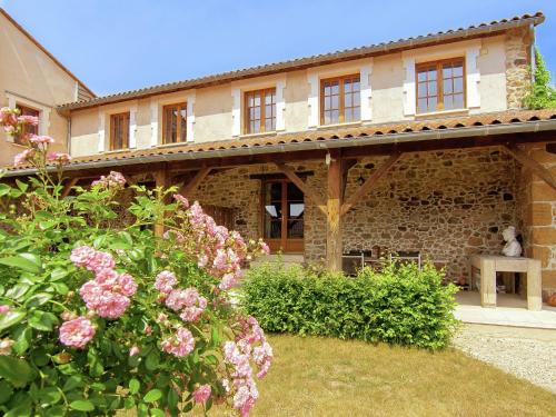 a stone house with pink flowers in the yard at Very nice cottage with studio on a domain with heated pool in Roussines