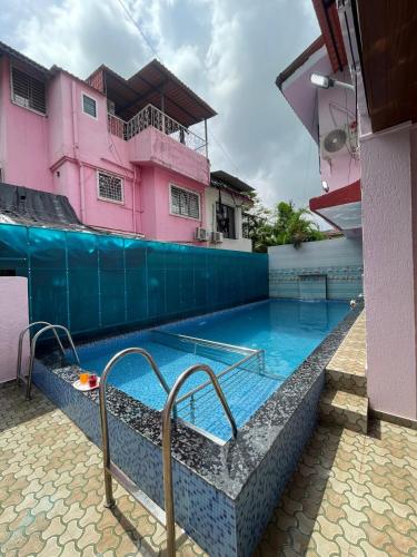 a swimming pool in front of a pink building at Amaani Villa in Lonavala
