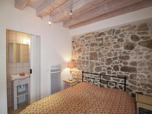 a bedroom with a stone wall and a bed at Very nice cottage with studio on a domain with heated pool in Roussines