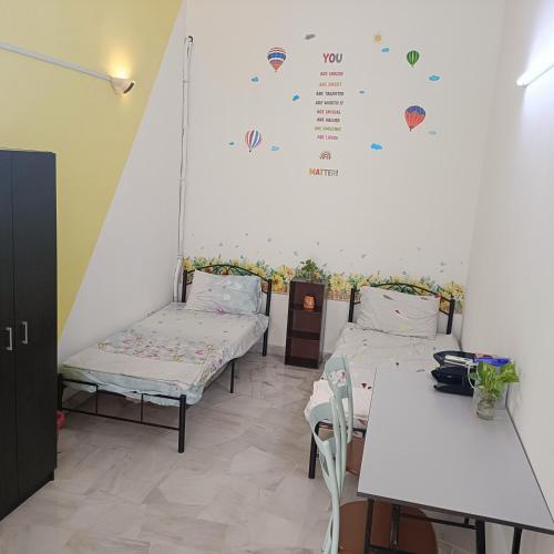 a room with two beds and tables and a wall at Sungai Long Homestay in Kajang