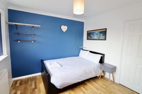 a bedroom with a blue wall and a bed at Addlestone Spacious Four Bedroom House in Addlestone