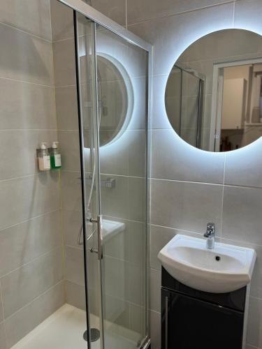 une salle de bain avec une douche, un lavabo et un miroir dans l'établissement Le Bleu Royal - Versailles, à Versailles