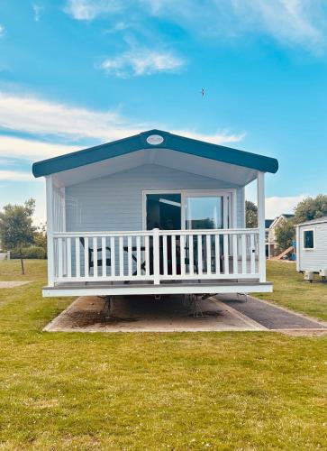 a mobile home with a blue roof and a porch at BEACH SIDE CARAVAN - haven - Caister on sea in Caister-on-Sea