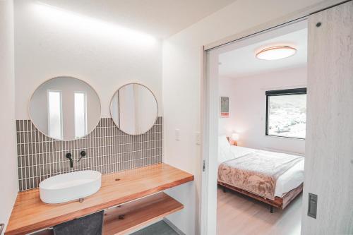 a bathroom with a sink and a bed and mirrors at Furano First Tracks - 5mins to ski field in Furano
