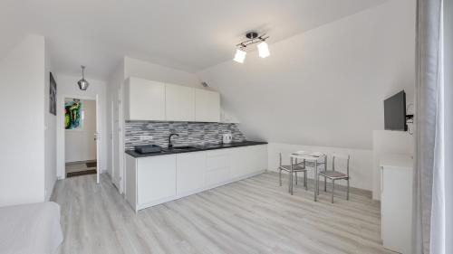 a kitchen with white cabinets and a table and chairs at Zasypane Mazury, Sun & Snow in Orło