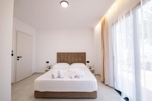 a white bedroom with a large bed with white sheets at Sunset Aparthotel in Sarandë