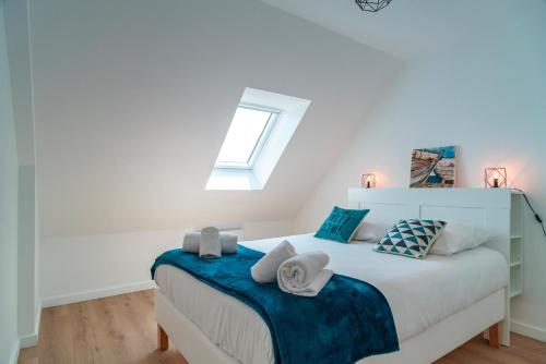 Un dormitorio con una cama blanca con toallas. en Le Haut du Nelud - Appt dans maison avec jardin, en Locmariaquer