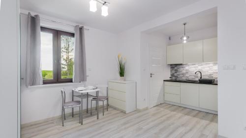 a kitchen with white cabinets and a table and chairs at Zasypane Mazury, Sun & Snow in Orło