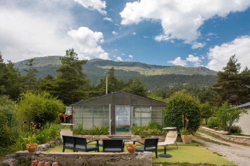 a greenhouse in the backyard of a house with mountains in the background at Nid Douillet très paisible in Saint-Auban