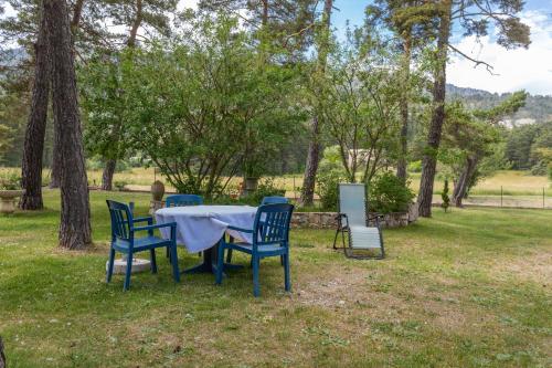 a table and chairs in a field with trees at Nid Douillet très paisible in Saint-Auban