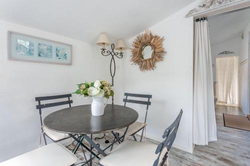 a dining room table with chairs and a vase of flowers at Nid Douillet très paisible in Saint-Auban