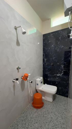 a bathroom with a toilet with an orange seat at GOKUL DELUXE Homestay in Māvalli