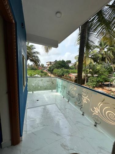 a balcony with a view of the ocean and palm trees at GOKUL DELUXE Homestay in Māvalli