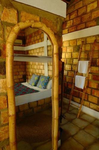 a bedroom with a bed in a brick wall at Lehani Beach Hostel in Praia do Tofo