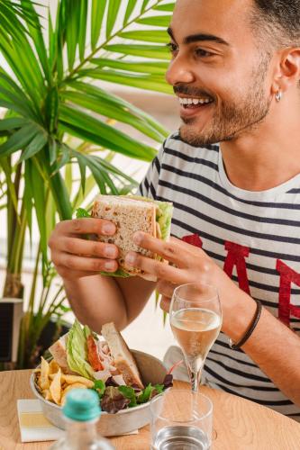 a man holding a sandwich in front of a plate of food at Dotcampus Roma City Center in Rome