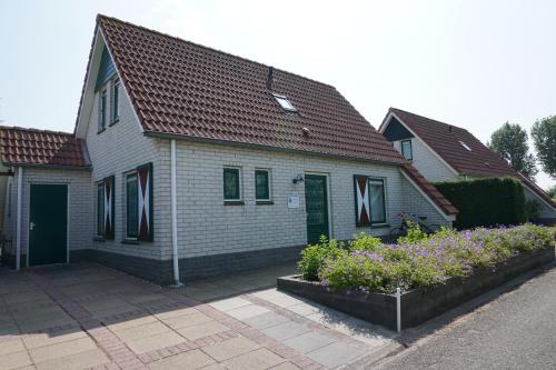a white house with a green door and some flowers at Kustverhuur, Park Schoneveld, Zeemeeuw 138 in Breskens