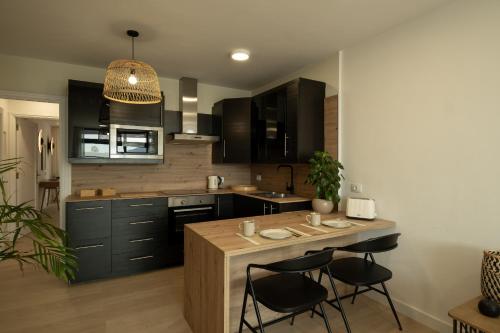 a kitchen with black cabinets and a island with stools at Almaré in Los Llanos de Aridane