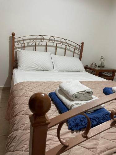 a bed with a wooden frame with towels on it at Poliana Holiday Home in Kotrónion