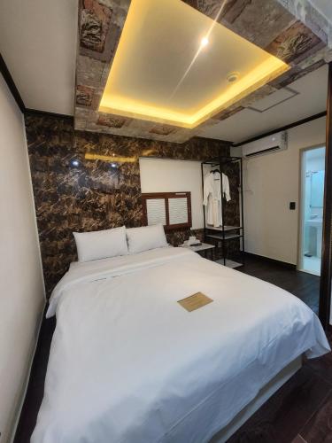 a large white bed in a room with a stone wall at Hotel BnB in Daejeon