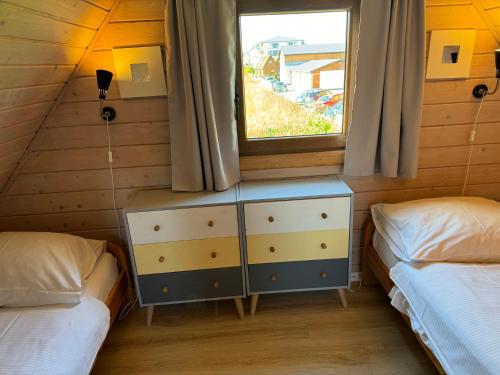 a bedroom with two twin beds and a window at KORALIA Domki Standard z basenem in Sarbinowo