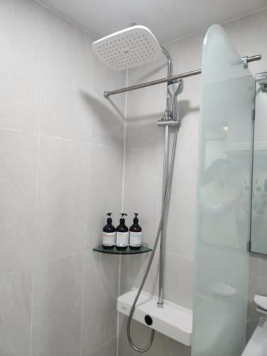 a bathroom with a shower with three bottles on a shelf at Hotel BnB in Daejeon