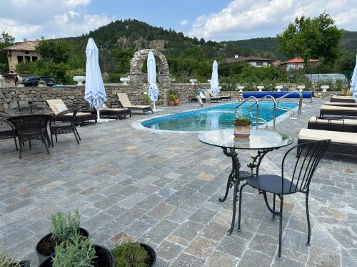 a patio with a table and chairs and a pool at Къща за гости Casa La Tinozza in Hisarya