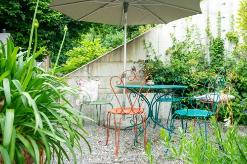a table and chairs with an umbrella in a garden at Gästehaus Belle5 in Bellerive